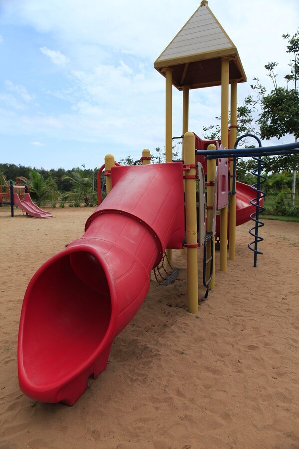 Un parque infantil con un tobogán rojo y una estructura amarilla para escalar.