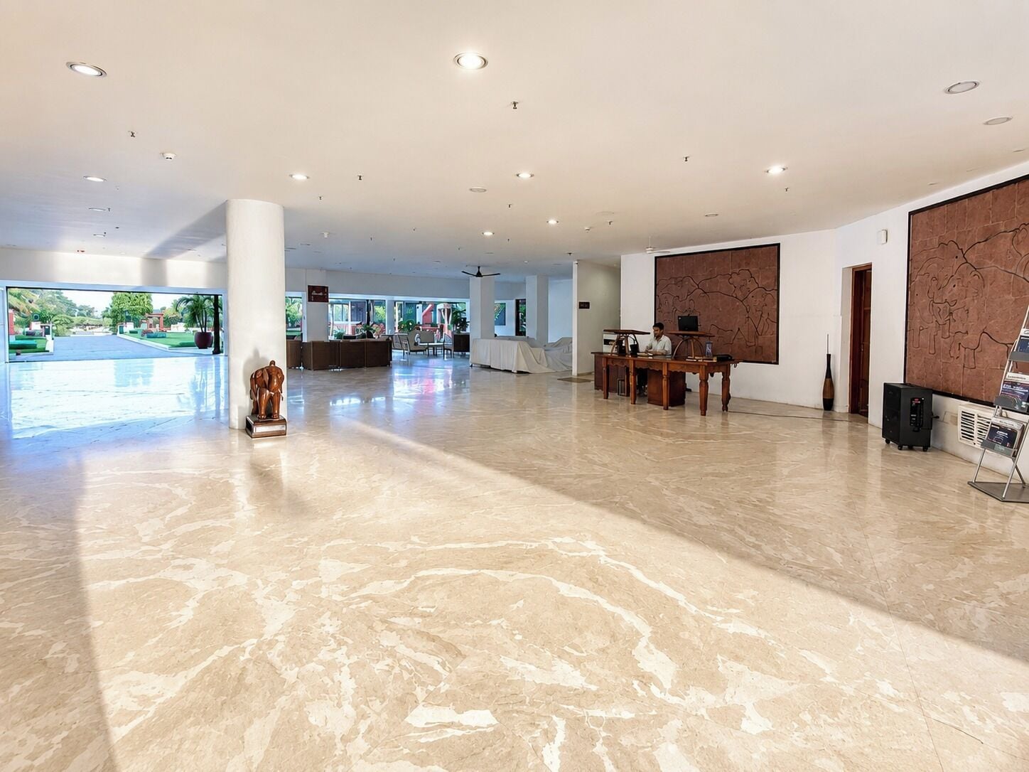 A spacious lobby with a marble floor, a reception desk, and a large wall mural.