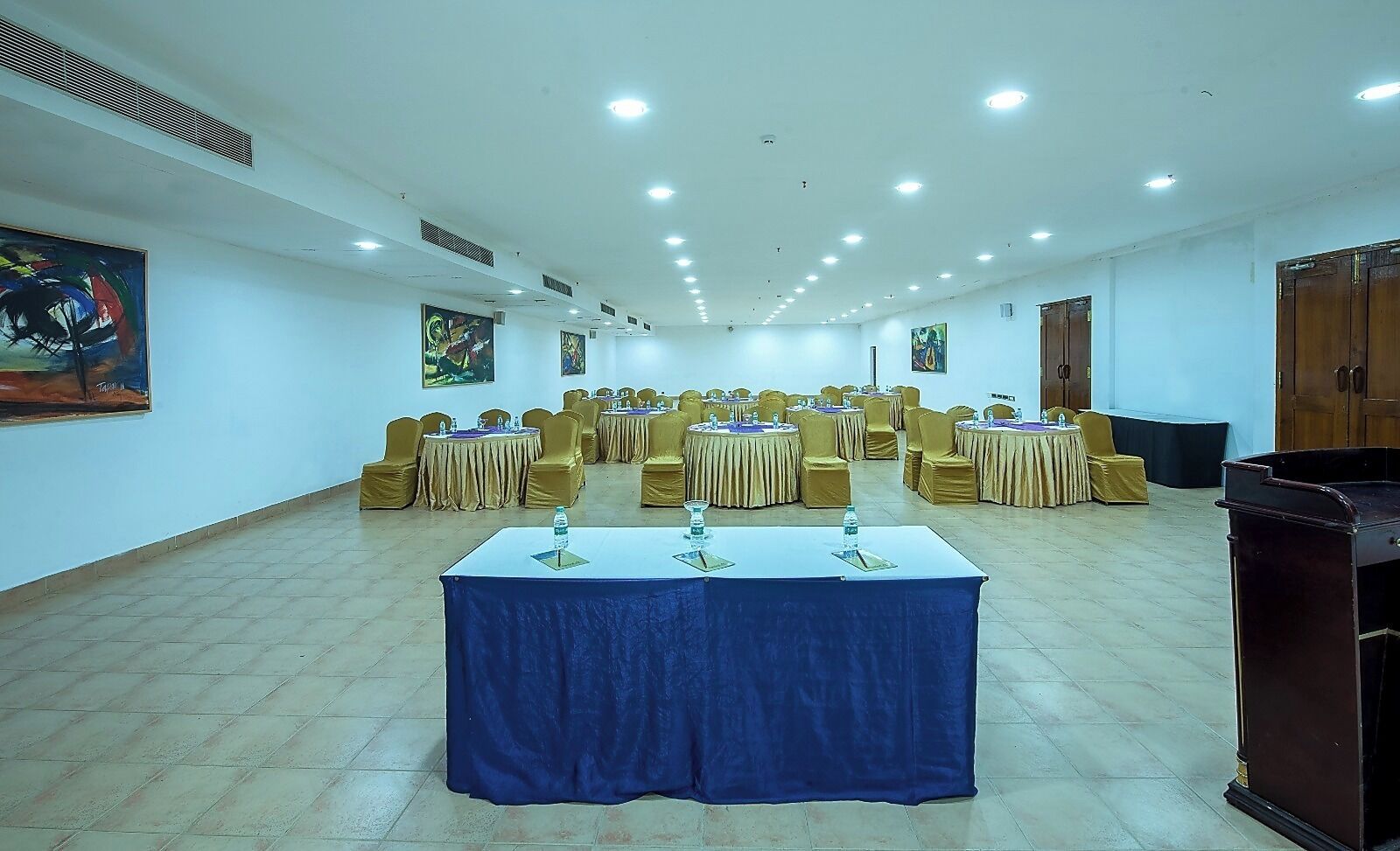 Uma sala de conferências com mesas redondas, cadeiras e um púlpito.