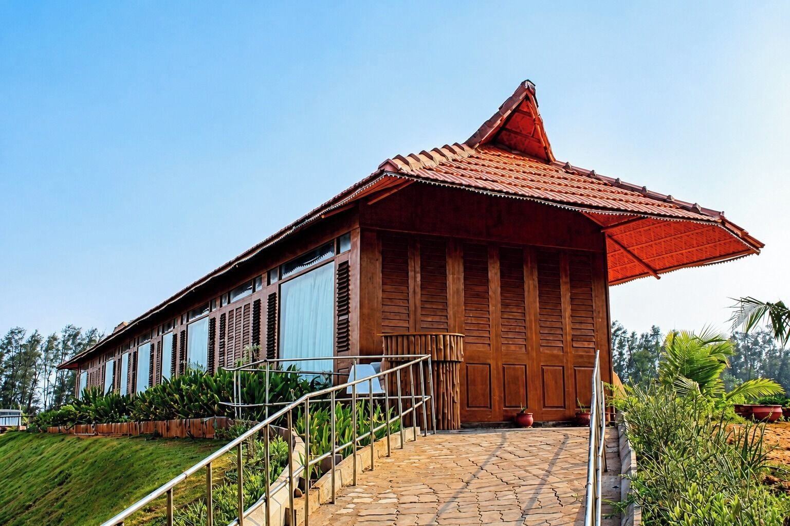 A two-story building with a red roof, large windows, and a staircase leading to the entrance.