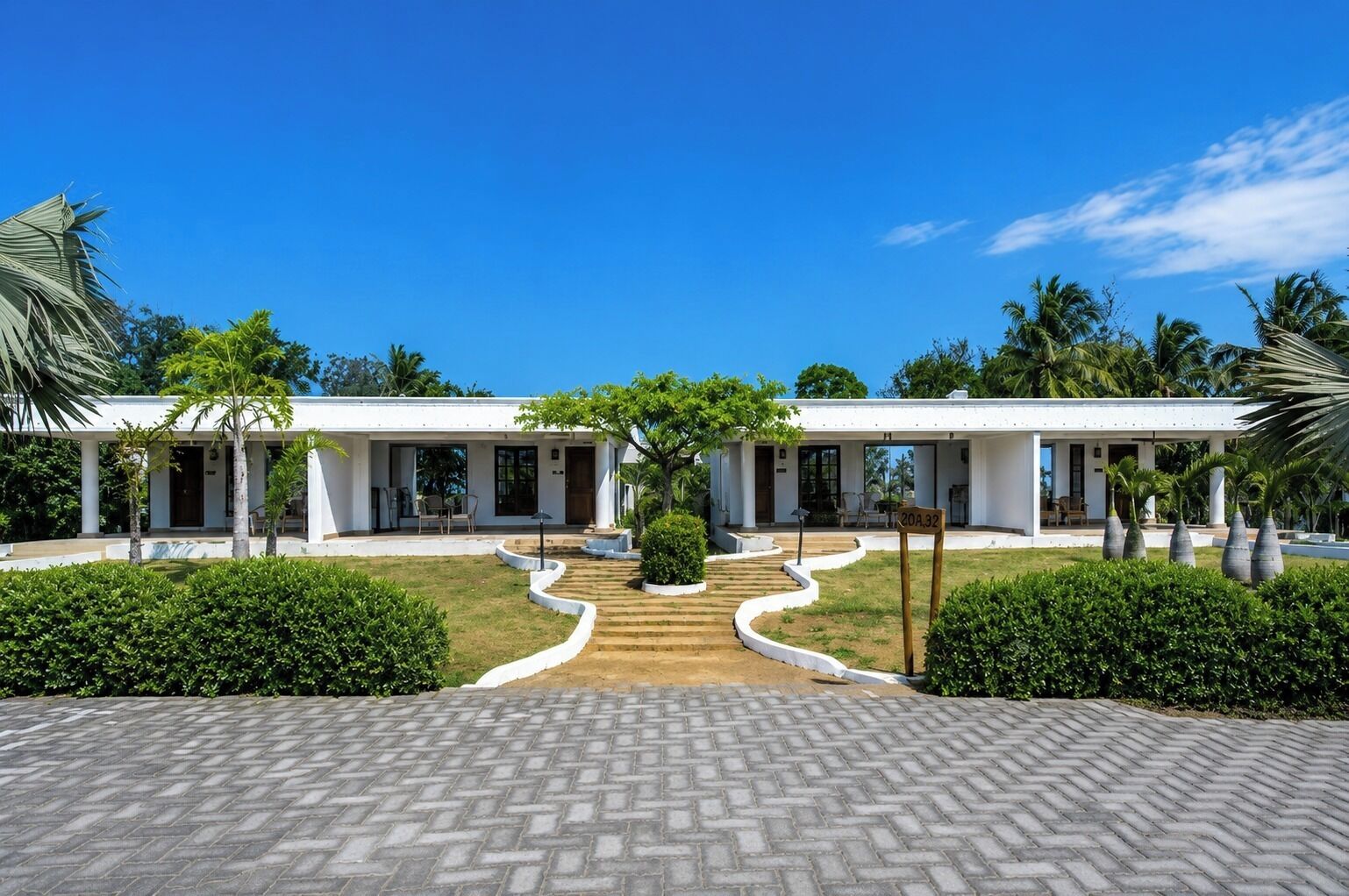 A modern two-story building with a symmetrical design, featuring a central pathway leading to a covered entrance.