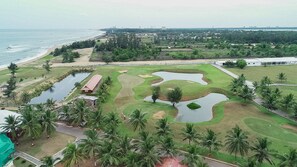 A golf course with multiple water hazards, a clubhouse, and a view of the ocean.
