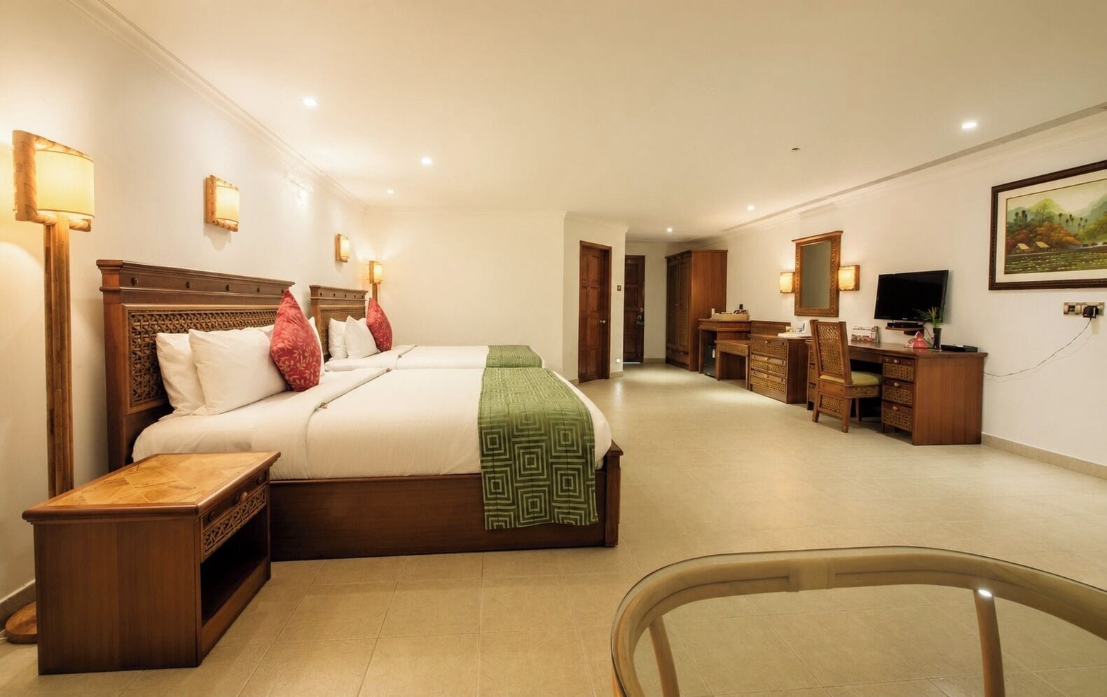 Une chambre d’hôtel avec un grand lit, des tables de chevet, un bureau avec une chaise, une télévision et un tableau au mur.