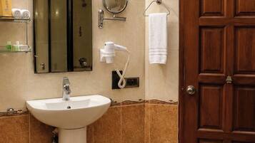 A bathroom with a sink, mirror, towel rack, and a door.