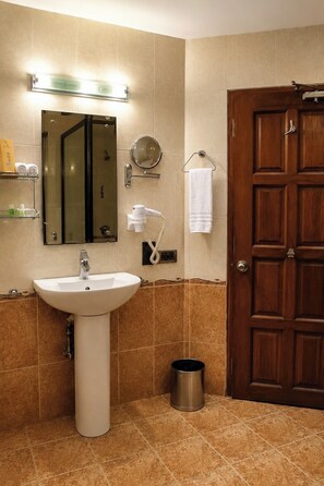 A bathroom with a sink, mirror, towel rack, and a door. - Chariot Beach Resort (Tirukalukundram)