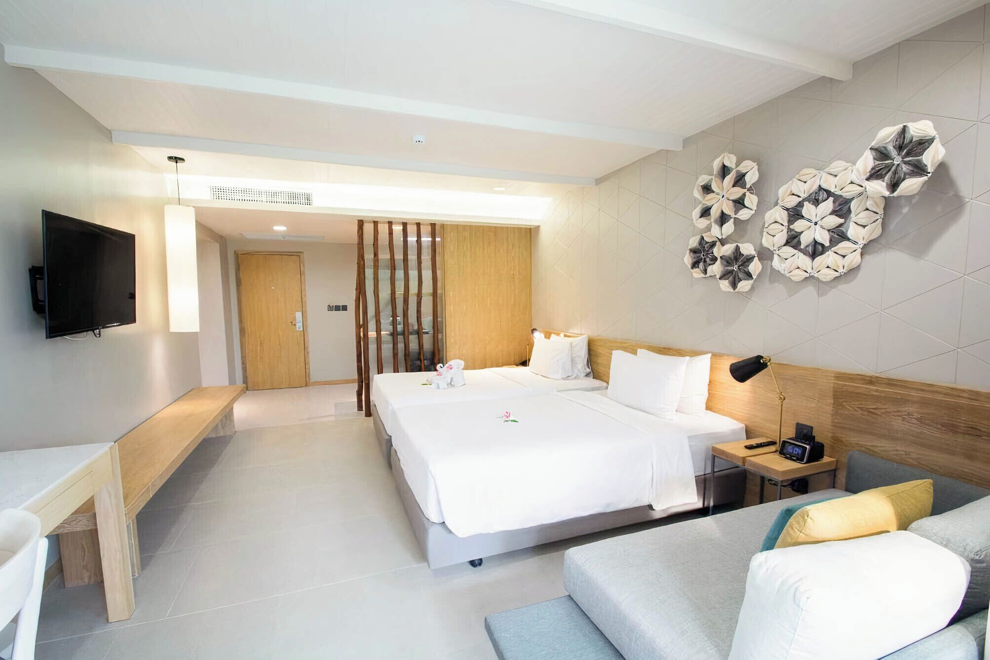 A hotel room with a bed, bedside table, TV, and decorative wall art.