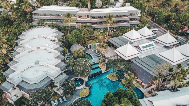 An aerial view of a resort with multiple buildings, a central swimming pool, and surrounding greenery. - Andaman Cannacia Resort & Spa (Karon)