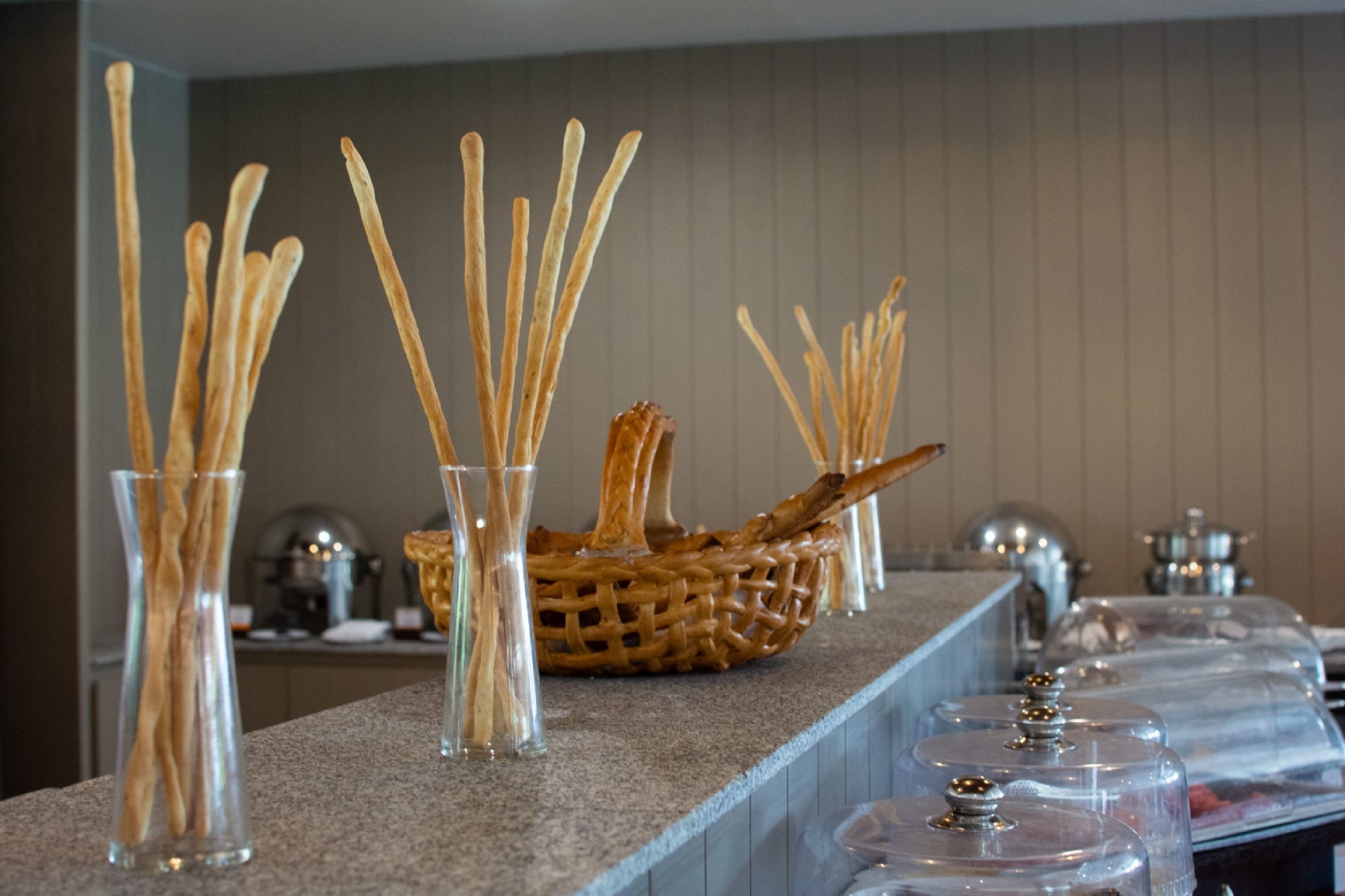 A buffet setup with clear glasses and baskets of breadsticks.