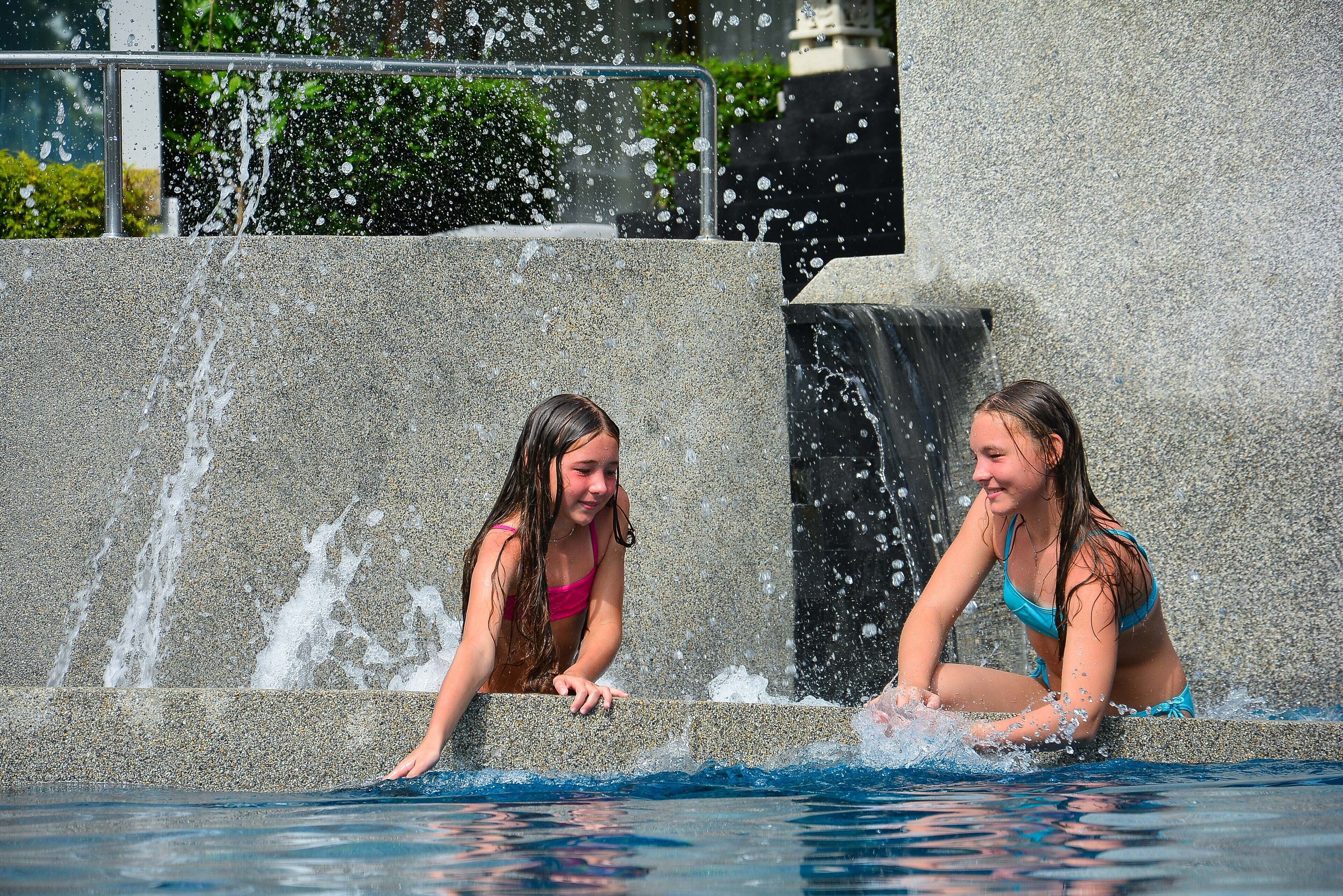 Two individuals in a swimming pool with water jets.