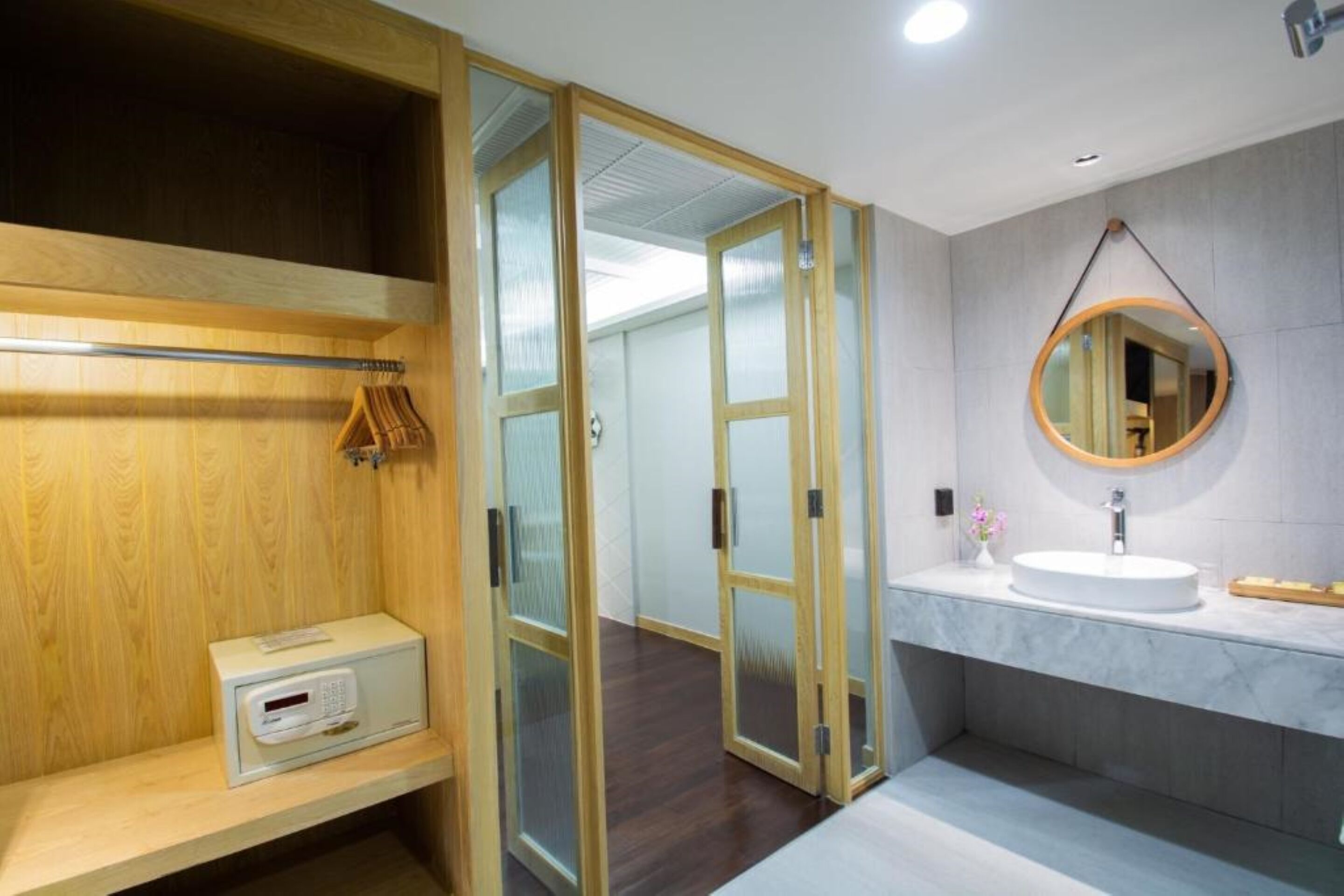 A modern bathroom with a wooden vanity, a round mirror, and a built-in heater.