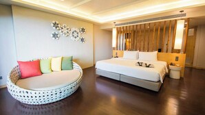 A modern hotel room with a large bed, a round seating area, and decorative wall art. - Andaman Cannacia Resort & Spa (Karon)