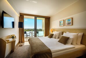 Habitación de hotel con una cama grande, un escritorio, un televisor y vistas al exterior.