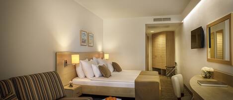 A hotel room with a bed, a sofa, a desk, and a chair.