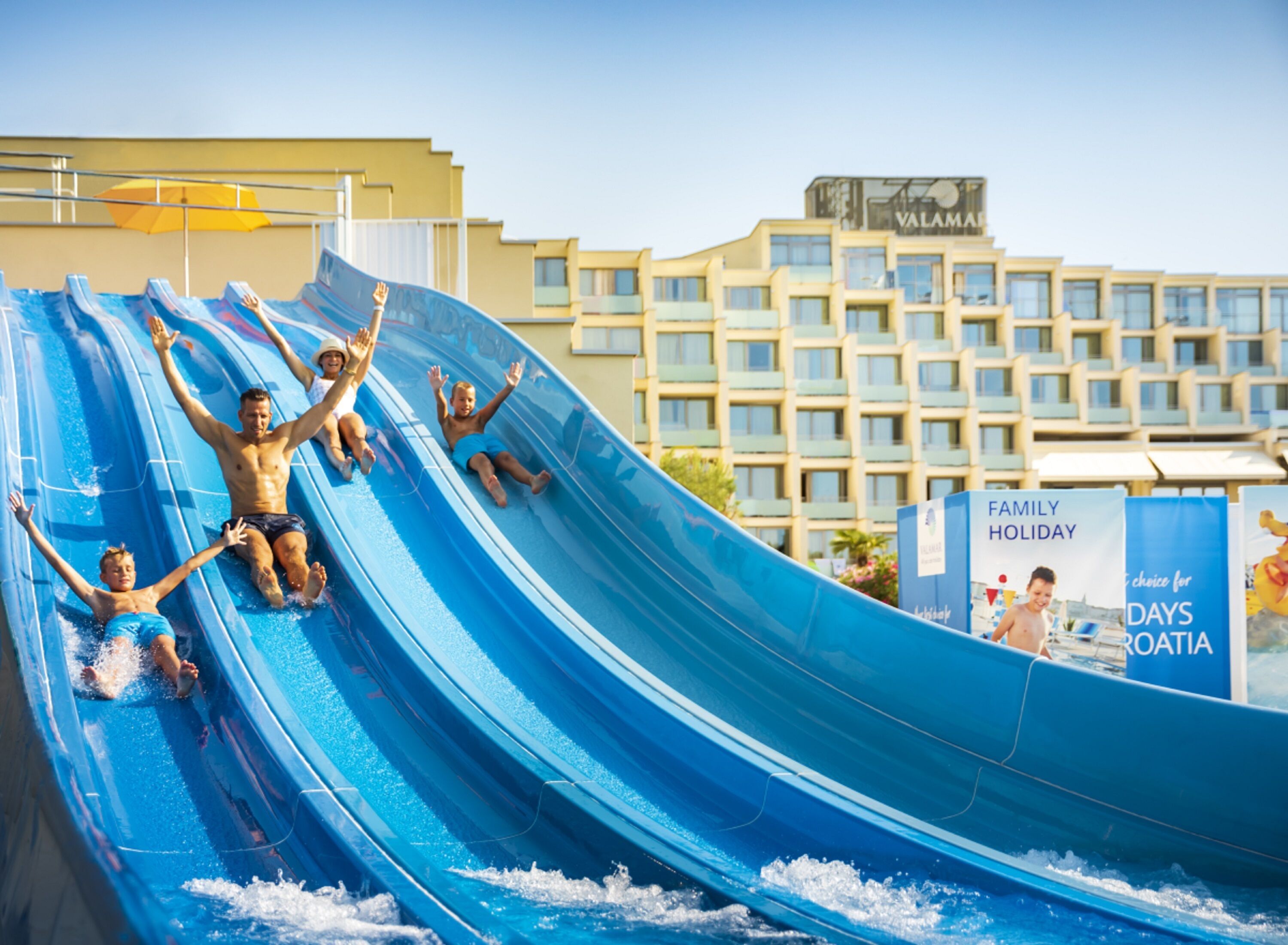 Eine Wasserrutsche in einem Resort, im Hintergrund ein Gebäude.