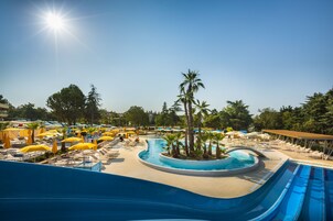 Zona de piscina en un resort, con varias piscinas, tumbonas y sombrillas.