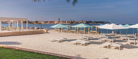 Vlak bij het strand, ligstoelen aan het strand, parasols, beachvolleybal