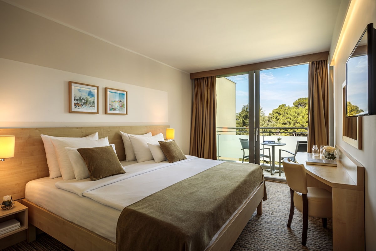Habitación de hotel con una cama grande, un escritorio y vistas al exterior.
