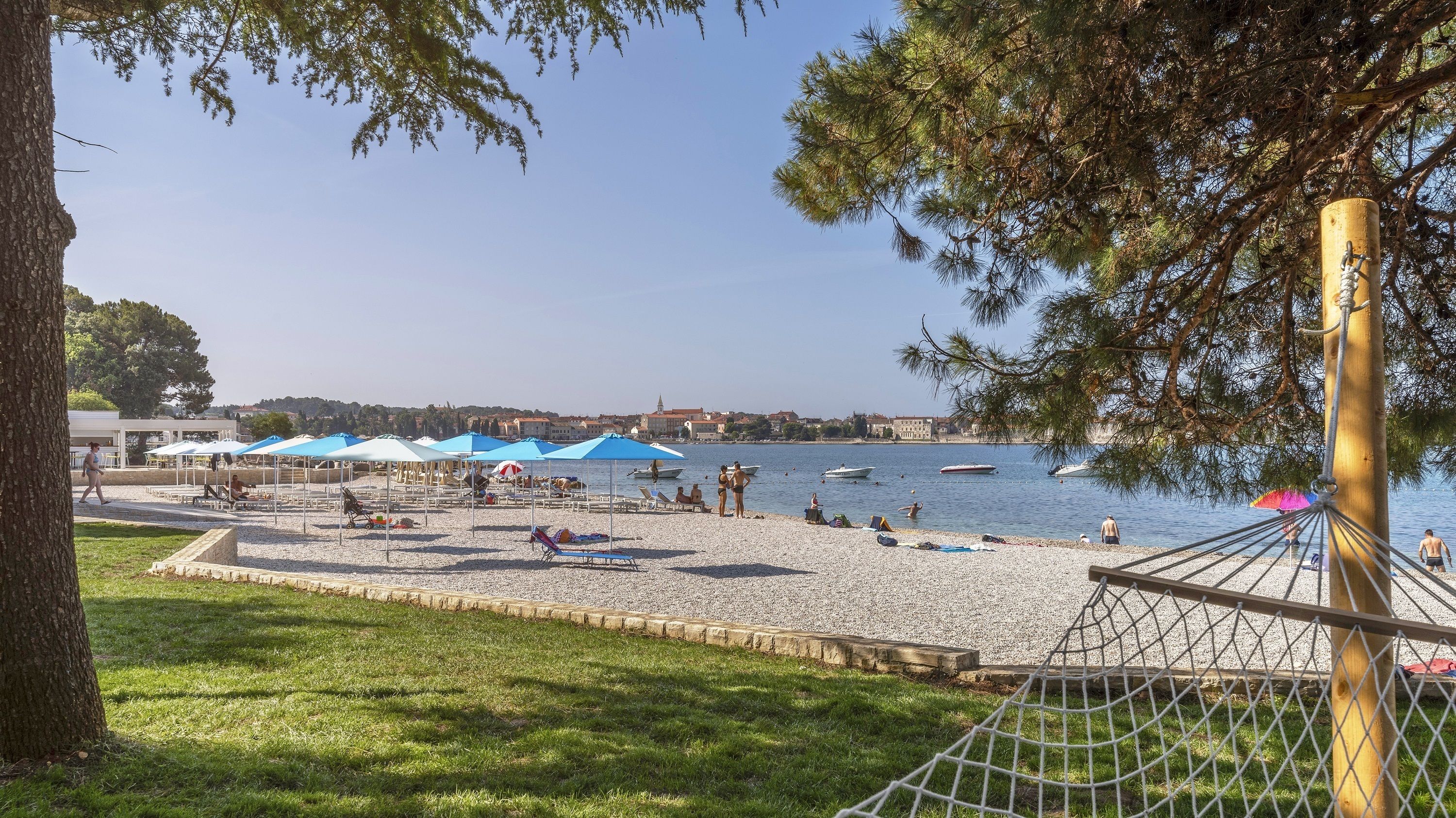 A beach with umbrellas, people, and boats.