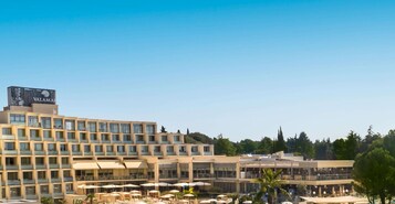 Un hotel moderno con varios pisos, ventanas amplias y zonas de estar al aire libre con sombrillas.