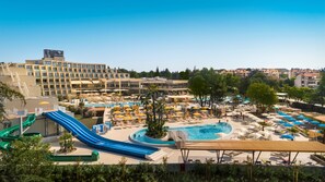 A hotel with a pool area, including a water slide and multiple lounge areas with umbrellas. - Valamar Parentino Hotel (Porec)