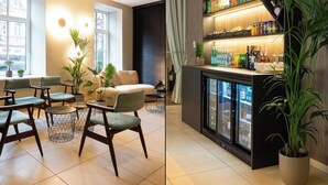 Un área de estar moderna con asientos, una barra con vitrina refrigerada y una escalera que conduce a un nivel inferior.