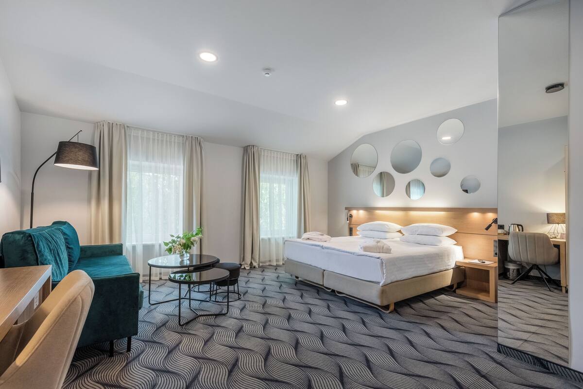 Una habitación de hotel moderna con cama, escritorio, sofá y mesa de comedor.