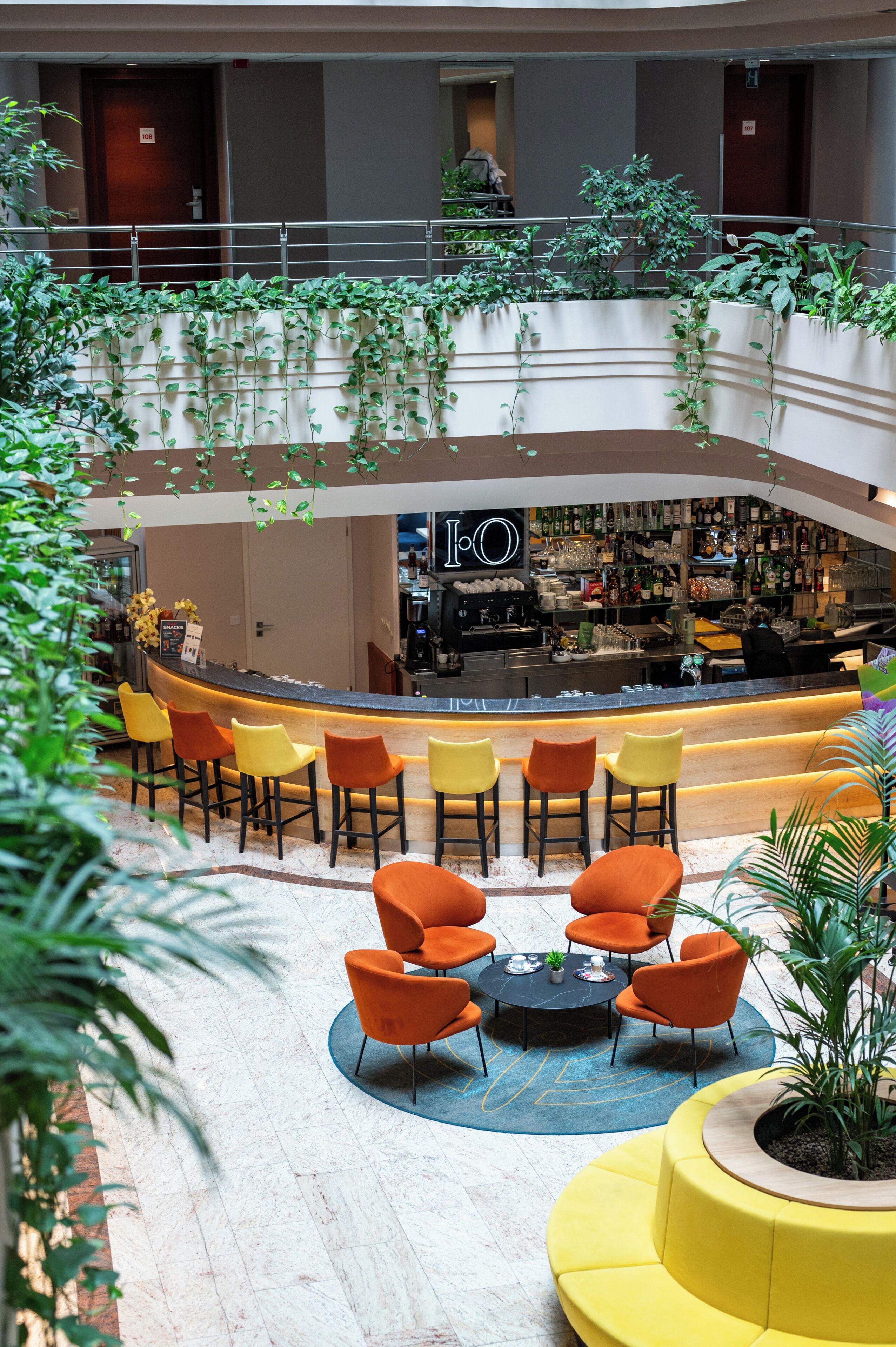 Een hotel lobby met een bar, zitplaatsen en binnenplanten.