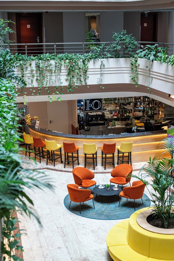 A hotel lobby with a bar area, seating, and indoor plants.