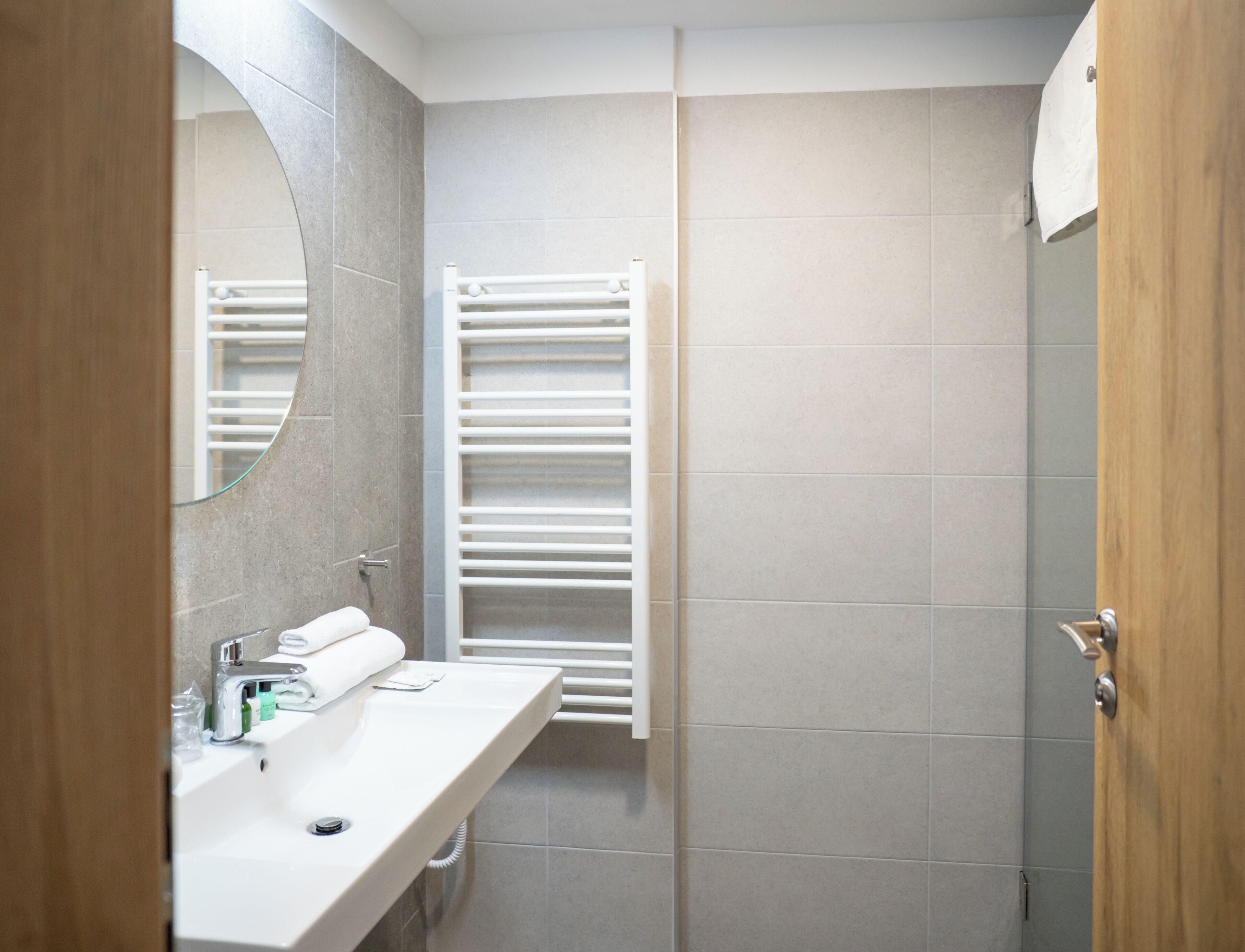 A bathroom with a white sink, a mirror, a towel rack, and a shower area.
