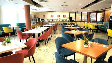 A restaurant with multiple tables and chairs, a kitchen area, and a seating area with a view.