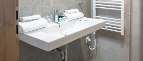 A modern bathroom with a large mirror, a white sink, and a towel rack.