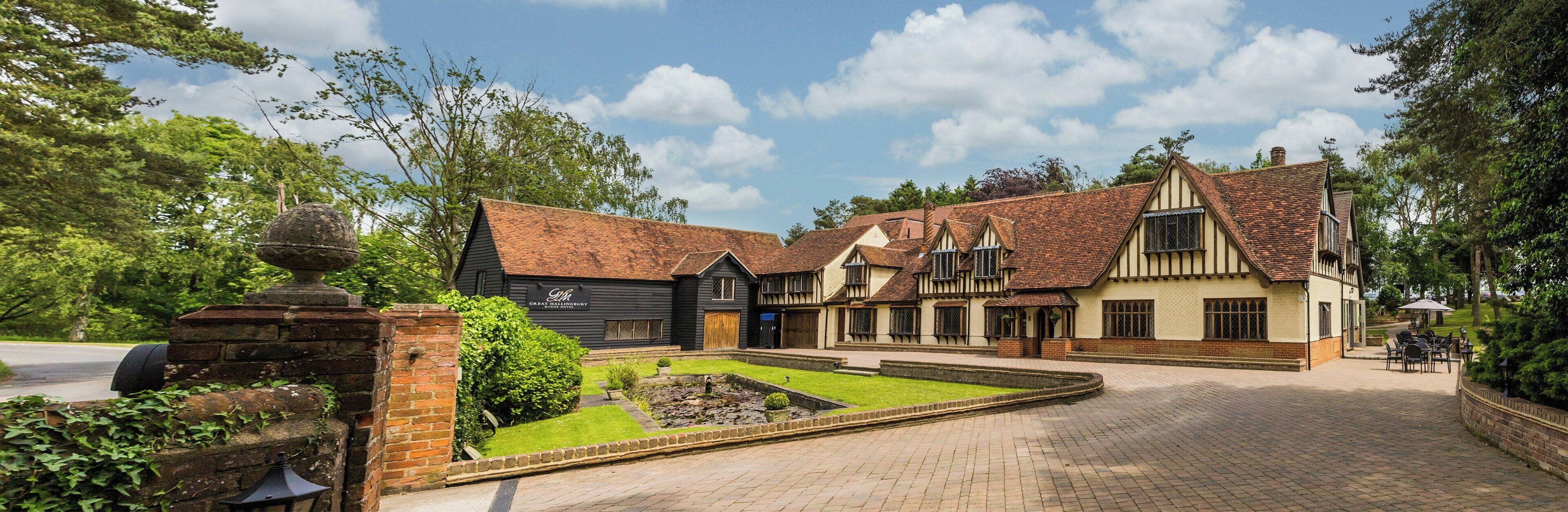 A traditional Tudor-style building with a courtyard, a well-maintained garden, and a brick pathway leading to the entrance.