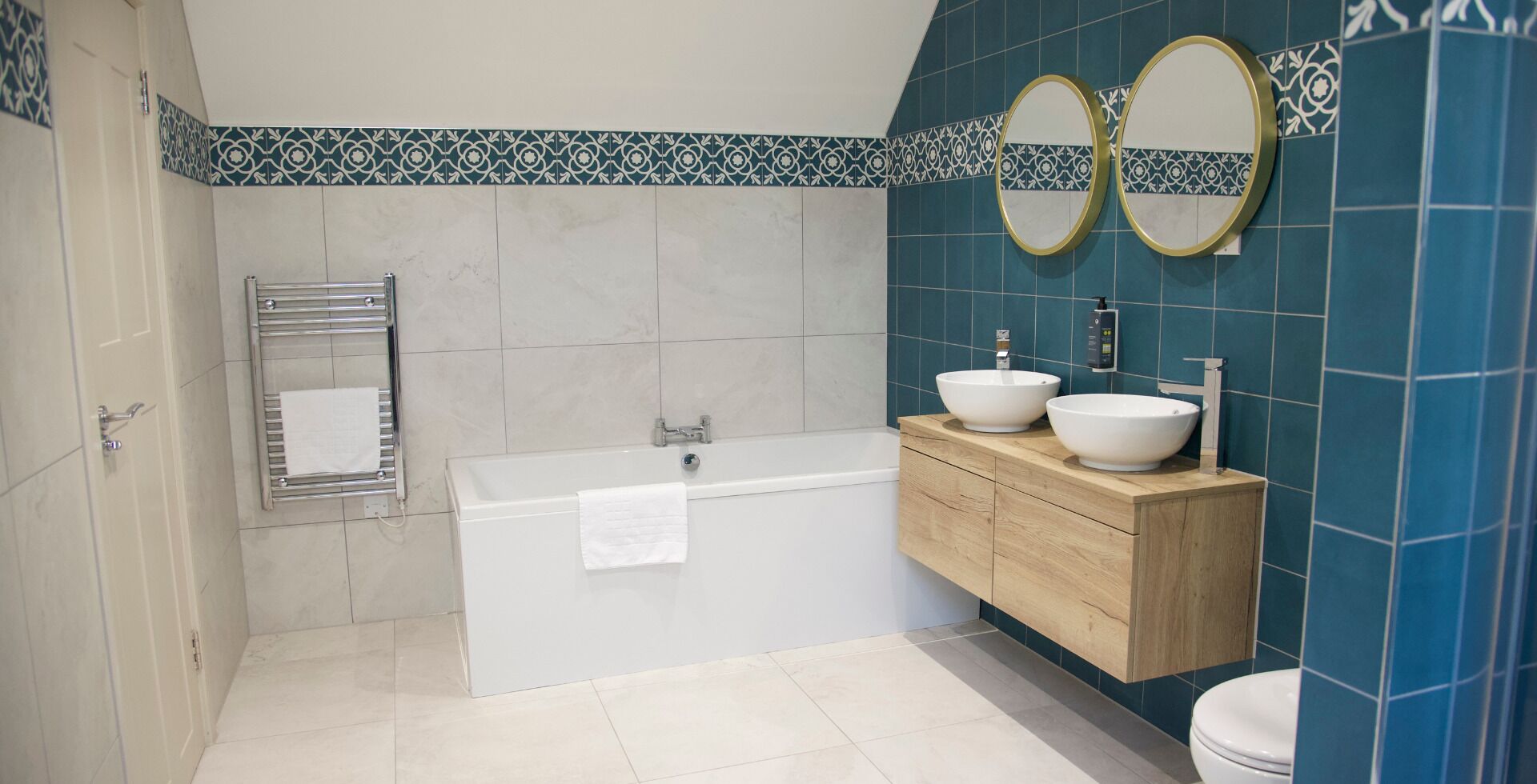 A modern bathroom with a bathtub, two sinks, and a toilet.