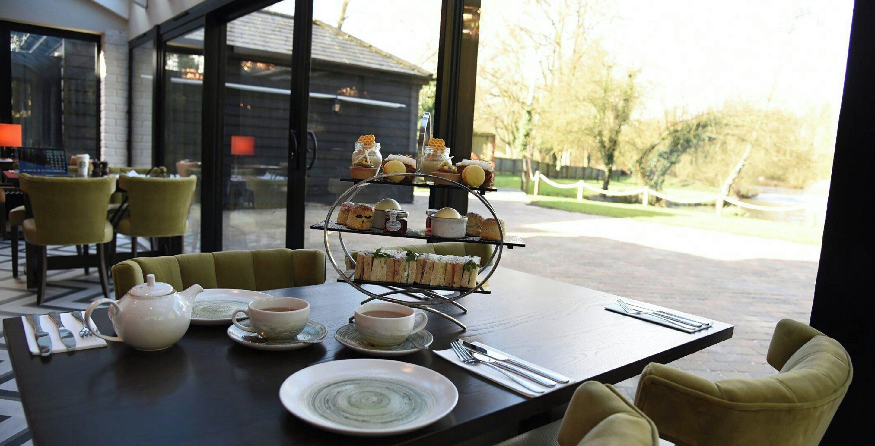 A table set with tea cups, a teapot, plates, and a tiered dessert stand.