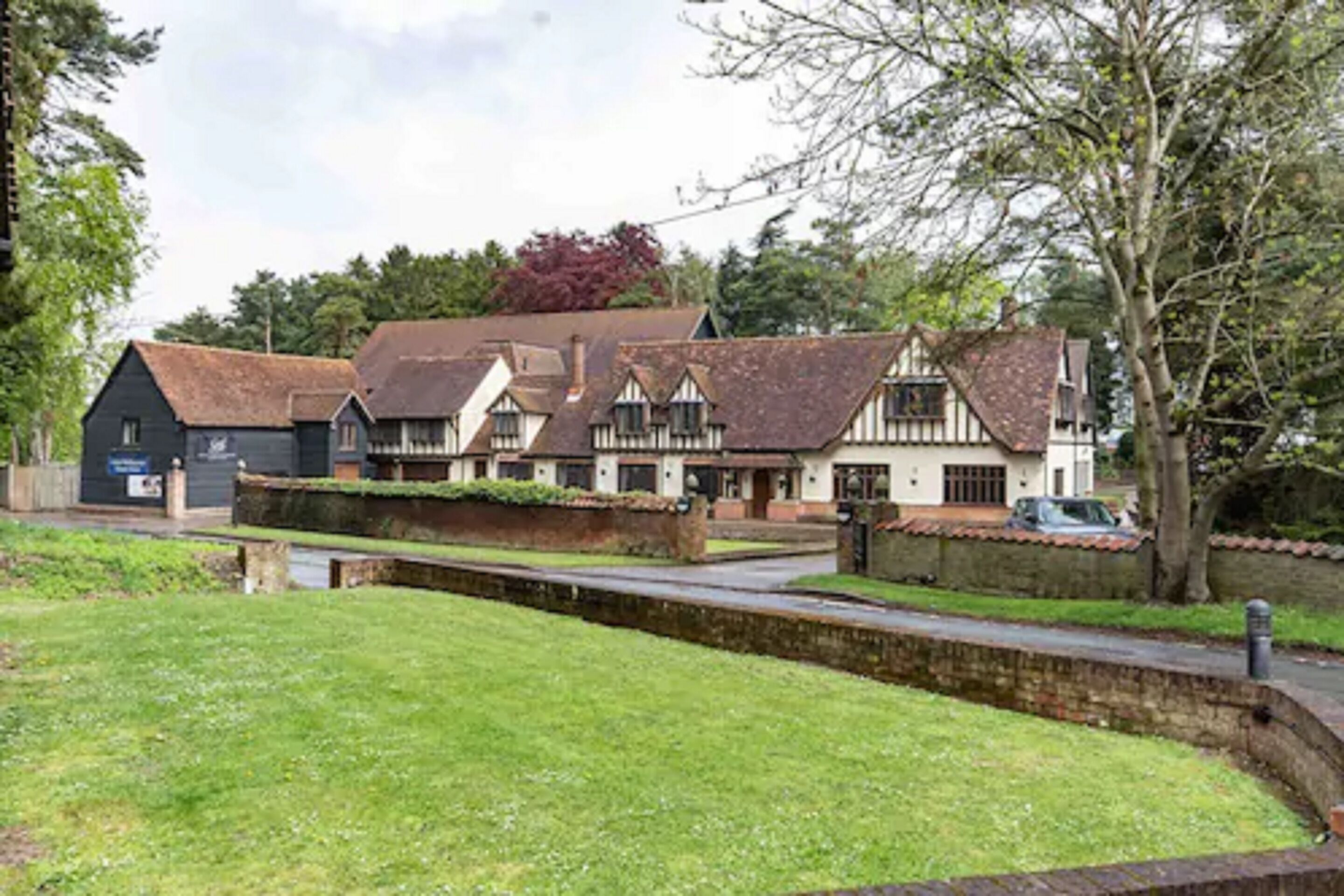A traditional building with multiple rooms, a grassy area in front, and a paved path.