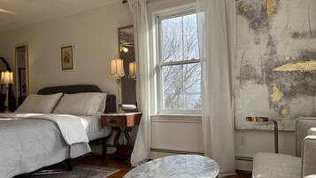 Une chambre à coucher comprenant un lit, une table de chevet, une lampe, un miroir, une fenêtre et une table basse en marbre.