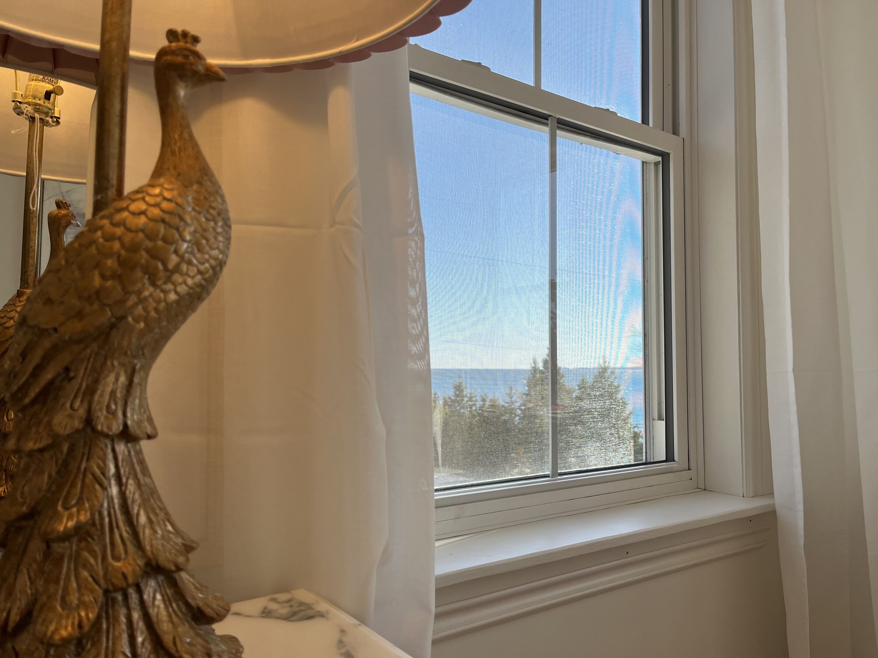 Una ventana con vista a árboles y cielo despejado.