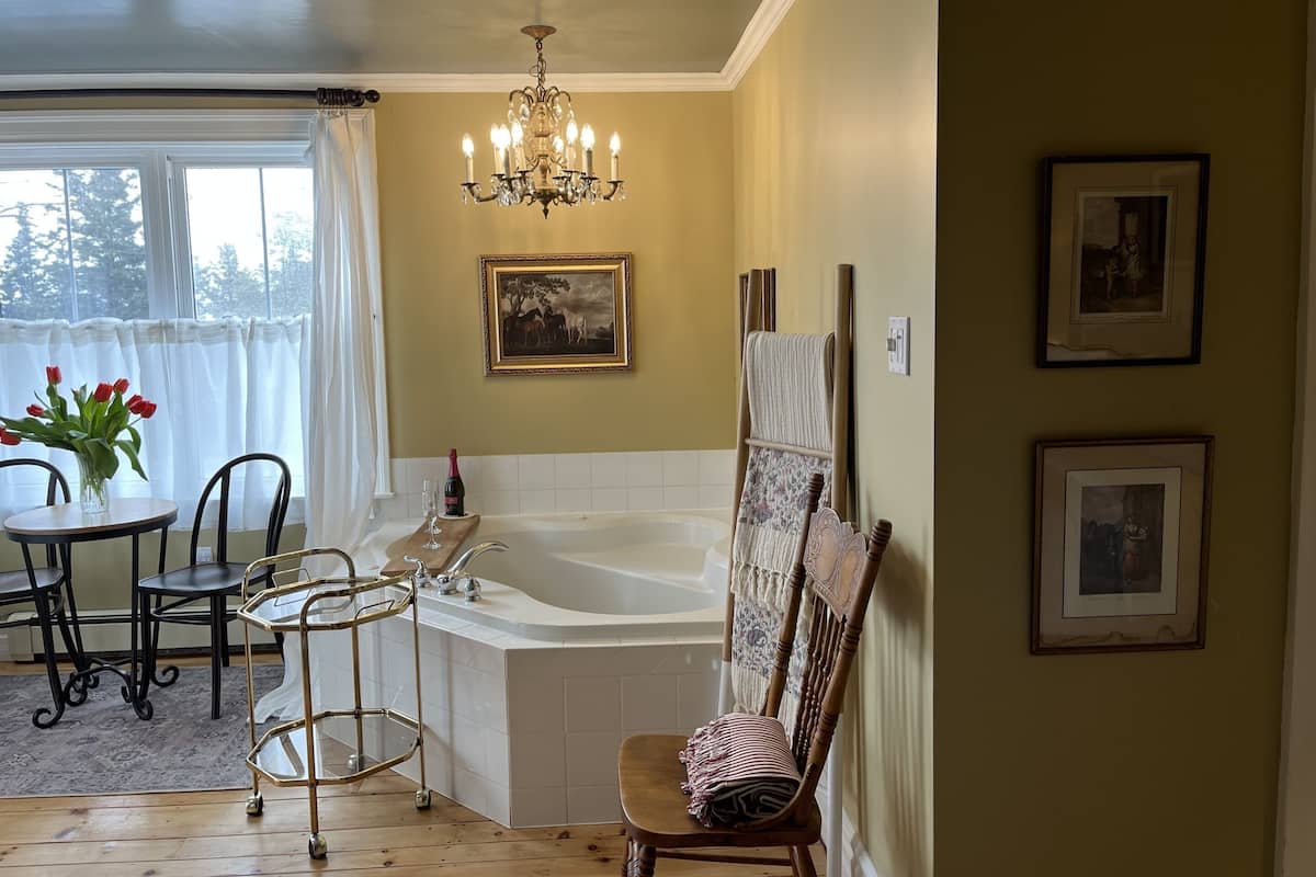 A bathroom with a bathtub, a chandelier, and framed pictures on the wall.
