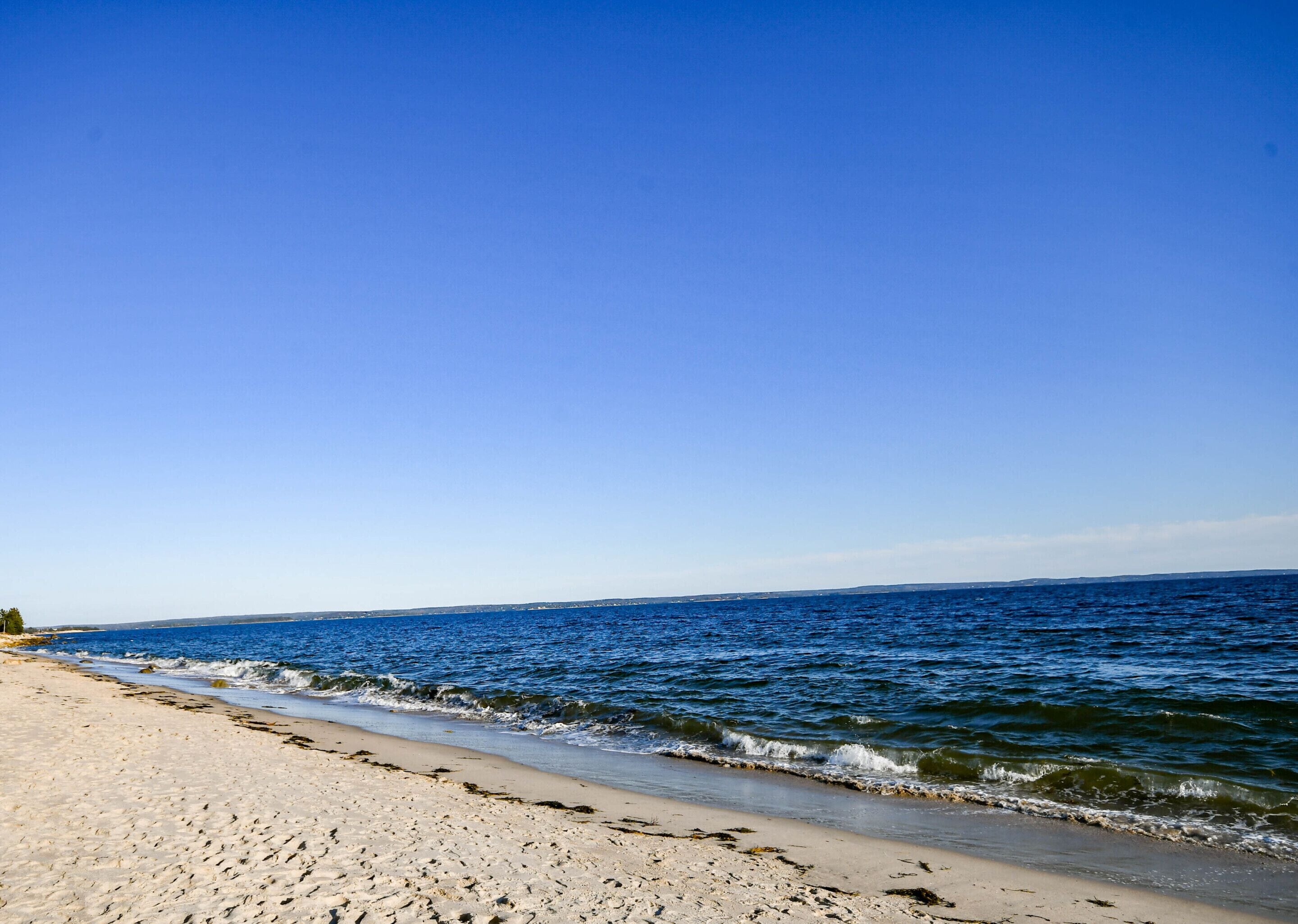 A beach with clear blue water and a sandy shore.