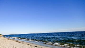 A beach with clear blue water and a sandy shore.