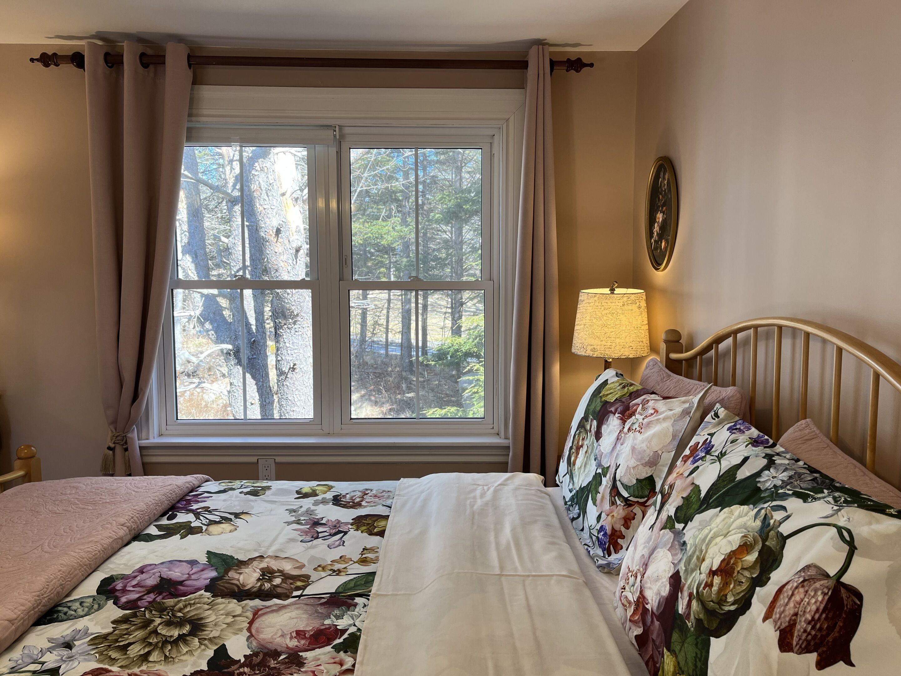 A bedroom with a bed, a nightstand, a lamp, and a window with curtains.
