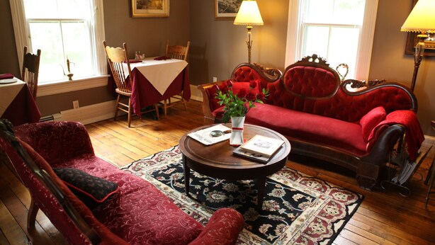 A cozy living room with a red sofa, a wooden coffee table, and a patterned rug.