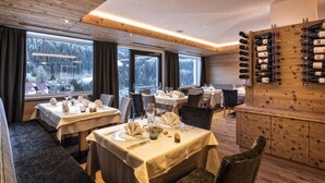 A restaurant with wooden interiors, large windows, and a wine rack. - Hotel Interski (Santa Cristina Val Gardena)