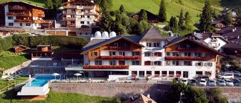 A hotel with multiple floors, outdoor swimming pool, and a parking area.
