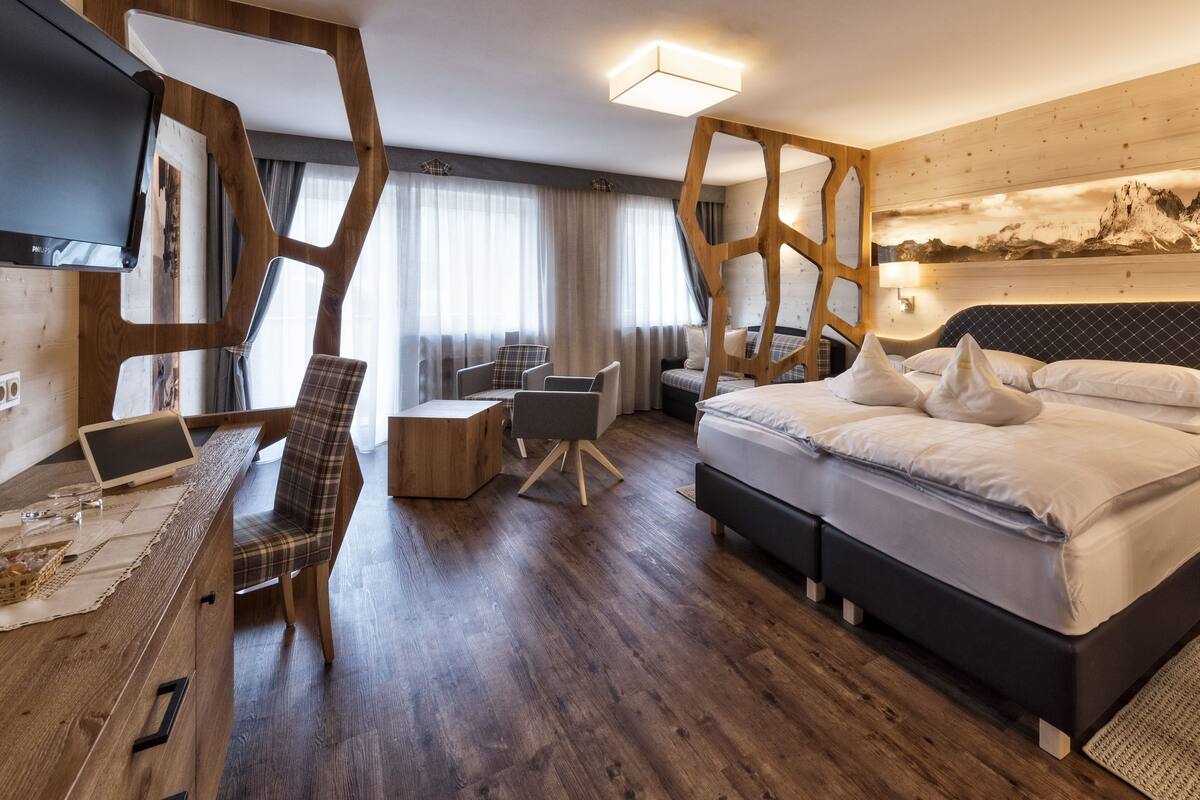 Una habitación de hotel moderna con una cama grande, un escritorio con una computadora portátil, una silla y un televisor.