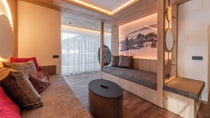 A modern living room with a wooden sofa, a round coffee table, and a wall-mounted TV. - Hotel Interski (Santa Cristina Val Gardena)