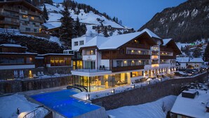 A multi-story hotel with a pool, surrounded by snow-covered mountains. - Hotel Interski (Santa Cristina Val Gardena)