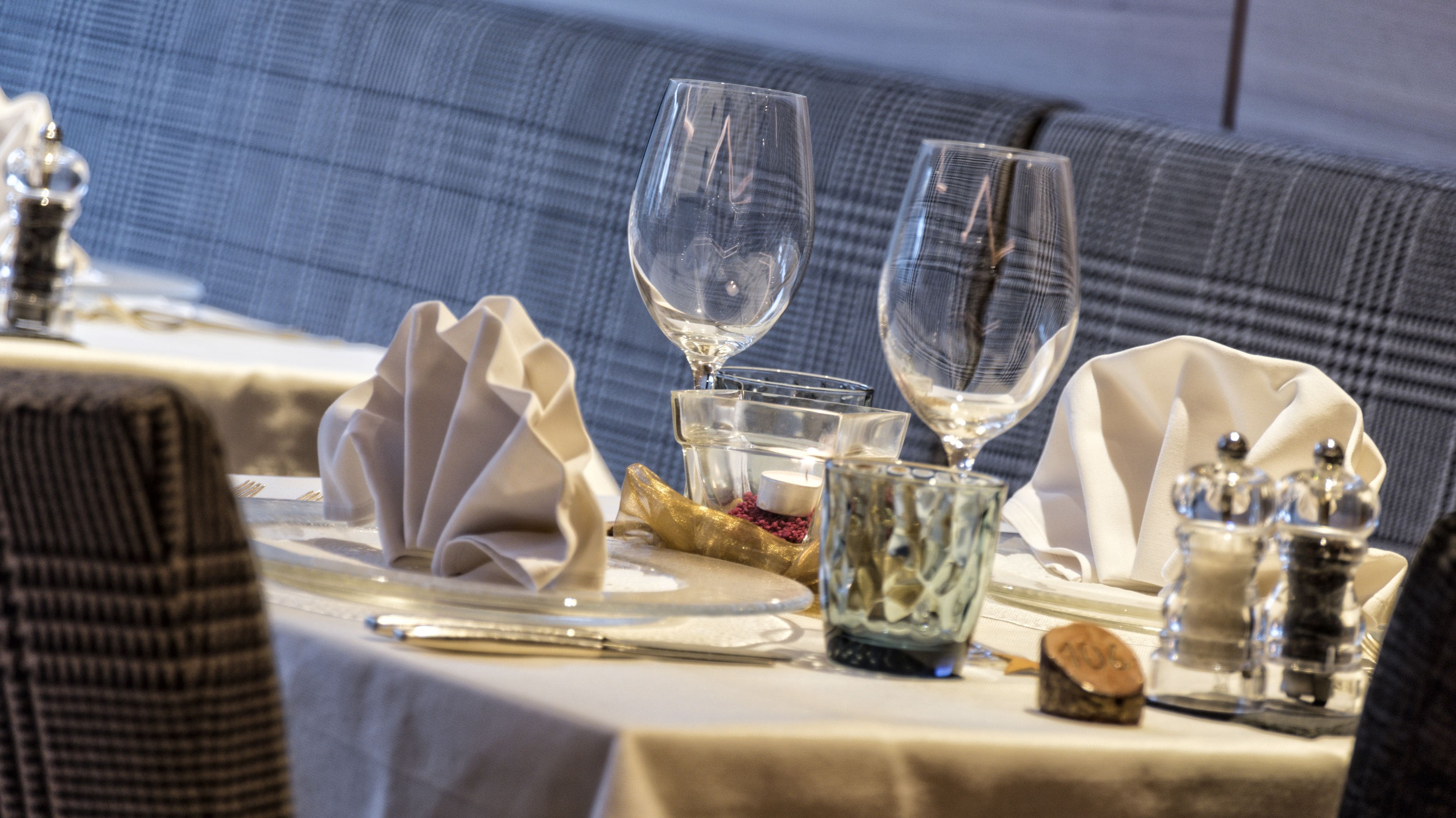 Une table mise pour un repas, avec de la belle verrerie, une bougie et une serviette décorative.