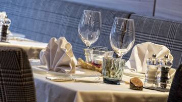 Une table mise pour un repas, avec de la belle verrerie, une bougie et une serviette décorative.