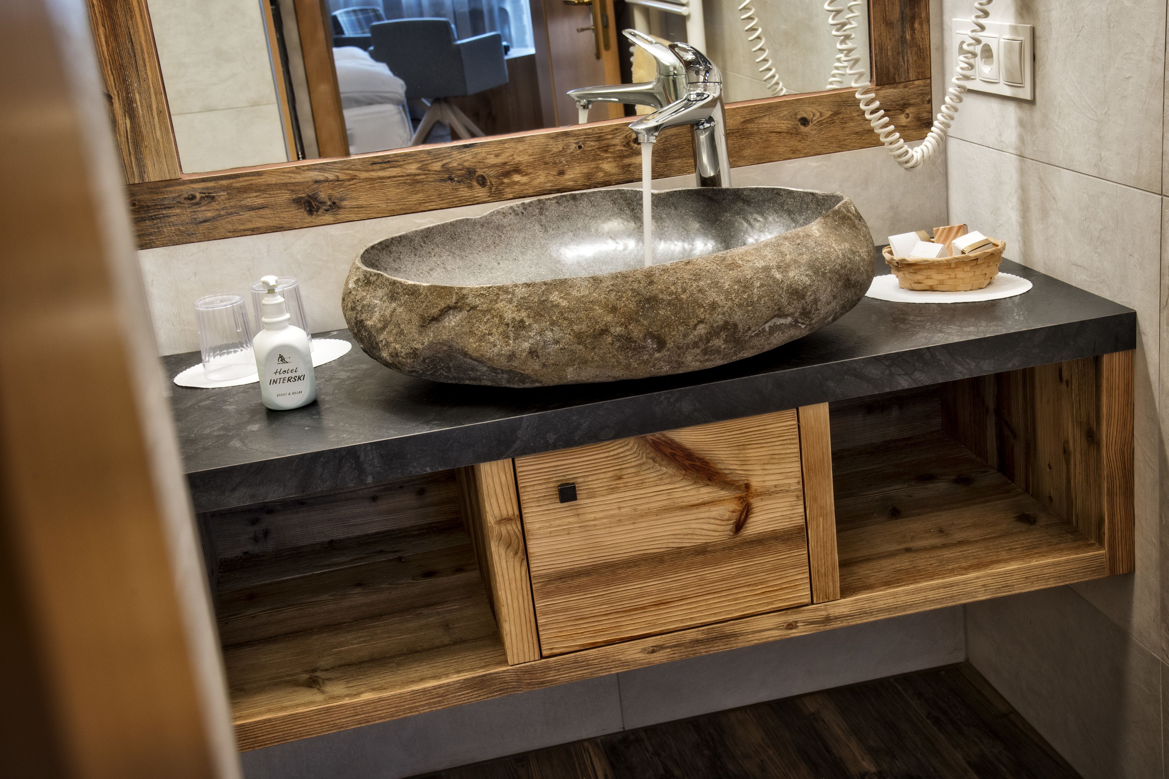 Un évier en pierre, un meuble-lavabo en bois, un miroir et un téléphone.